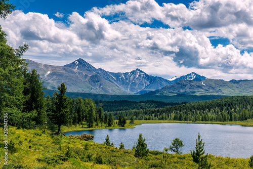 Mountain landscape, white clouds, lake and mountain range in the distance. Fantastic sunny day in mountains, large panorama. Location is in Altai, Russia. © exebiche
