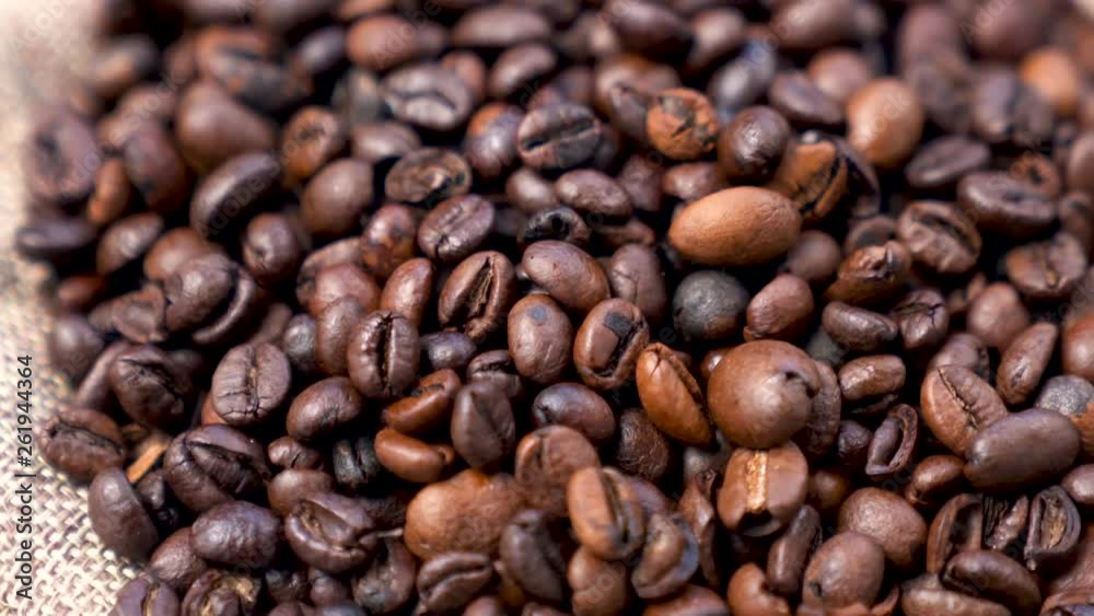 Black Coffee Grains. Black coffee is laid out on a bag spinning on a stand around its axis. Black Coffee Grains. Black coffee is laid out on a bag spinning on a stand around its axis.