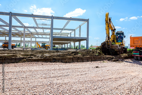 Backhoe is loading a truck with ground on building site photo