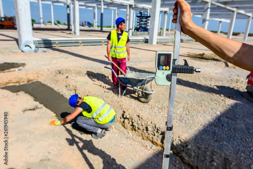 Worker is holding leveling rod to measuring level on construction site photo