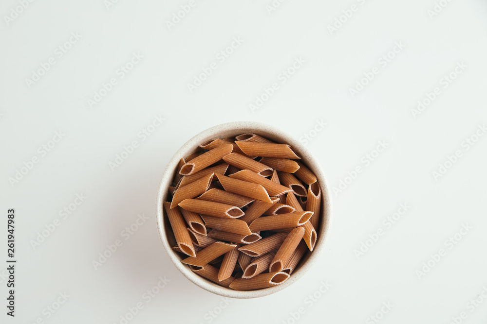 Whole grain macaroni on white background, top view Whole grain macaroni on white background, top view