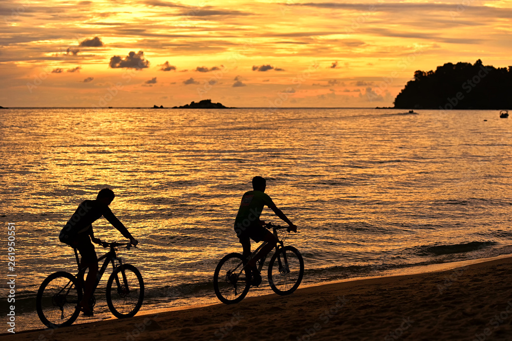 Fototapeta premium Two cyclist relaxing and enjoyed beautiful sunset along the beach in pangkor island, perak malaysia