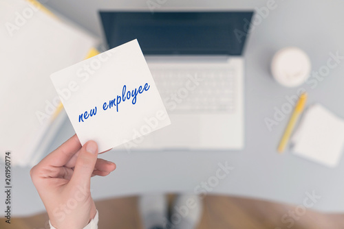 Woman clerk sitting holding note paper sticker with new employee phrase. Business concept. Concept.