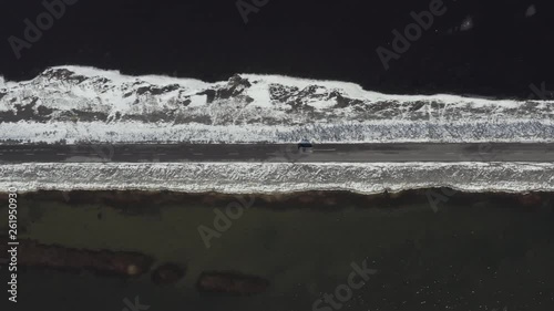 Bird's Eye View of a Car Driving Along a Narrow Road Crossing a Lake photo