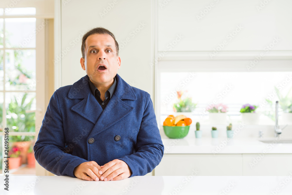 Middle age man sitting at home afraid and shocked with surprise expression, fear and excited face. Middle age man sitting at home afraid and shocked with surprise expression, fear and excited face.