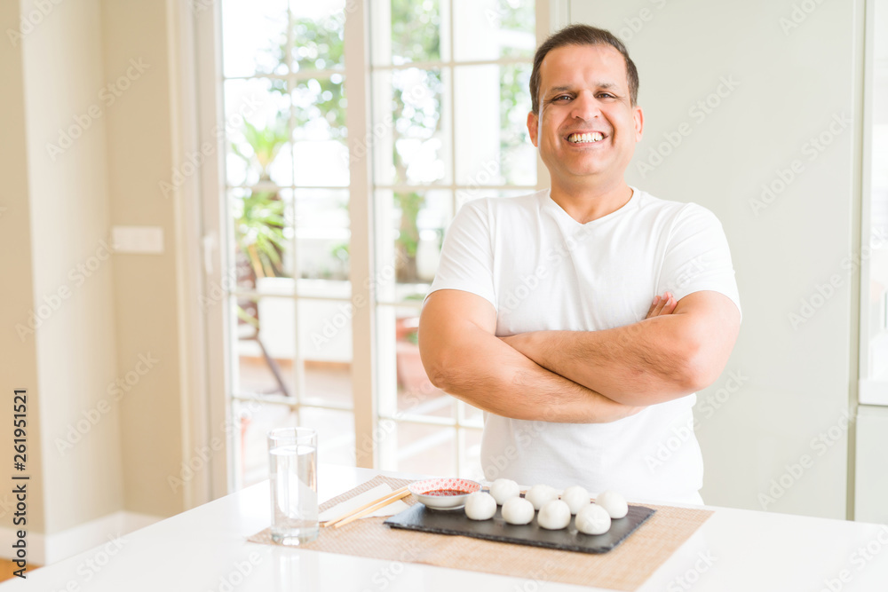 Middle age man eating asian dumplings at home happy face smiling with crossed arms looking at the camera. Positive person. Middle age man eating asian dumplings at home happy face smiling with crossed arms looking at the camera. Positive person.