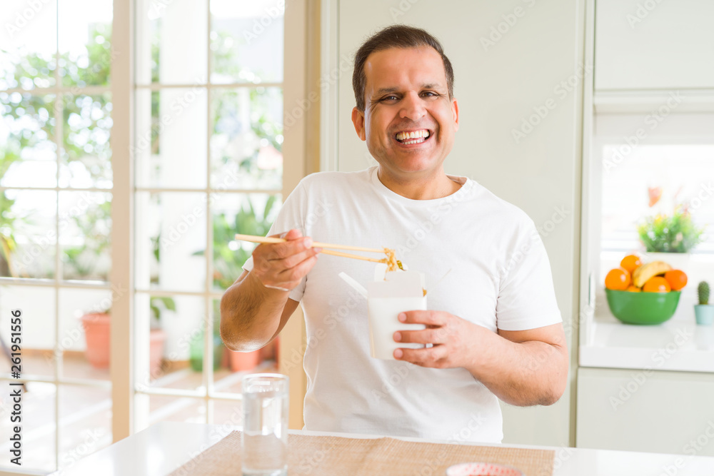 Middle age man eating take away noodles with choopsticks at home Middle age man eating take away noodles with choopsticks at home