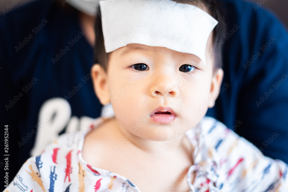 Unhappy Asian little baby sick with cool fever jel pad on forehead Unhappy Asian little baby sick with cool fever jel pad on forehead