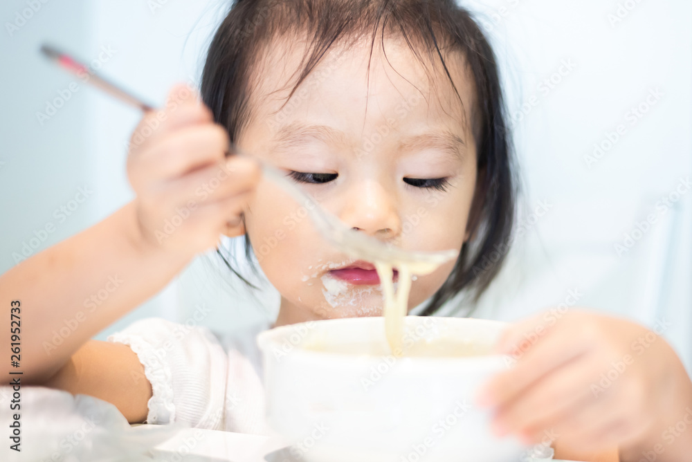 Asian little baby child eating noodle and enjoy breakfast by herself Asian little baby child eating noodle and enjoy breakfast by herself