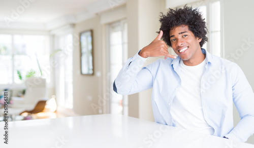 African American man at home smiling doing phone gesture with hand and fingers like talking on the telephone. Communicating concepts.