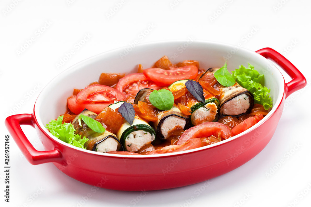 Eggplant with cheese baked with vegetables in a red bowl on a white background. Eggplant with cheese baked with vegetables in a red bowl on a white background.