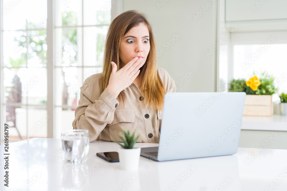 Beautiful young woman using computer laptop cover mouth with hand shocked with shame for mistake, expression of fear, scared in silence, secret concept Beautiful young woman using computer laptop cover mouth with hand shocked with shame for mistake, expression of fear, scared in silence, secret concept