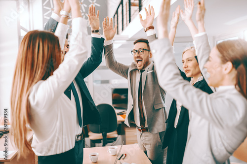Wall Mural Group of cheerful corporate businesspeople in formal wear stacking hands at meeting in boardroom