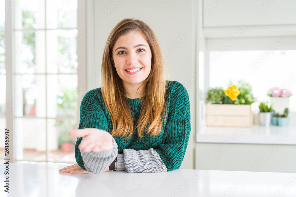 Young beautiful plus size woman wearing casual striped sweater smiling cheerful offering palm hand giving assistance and acceptance. Young beautiful plus size woman wearing casual striped sweater smiling cheerful offering palm hand giving assistance and acceptance.