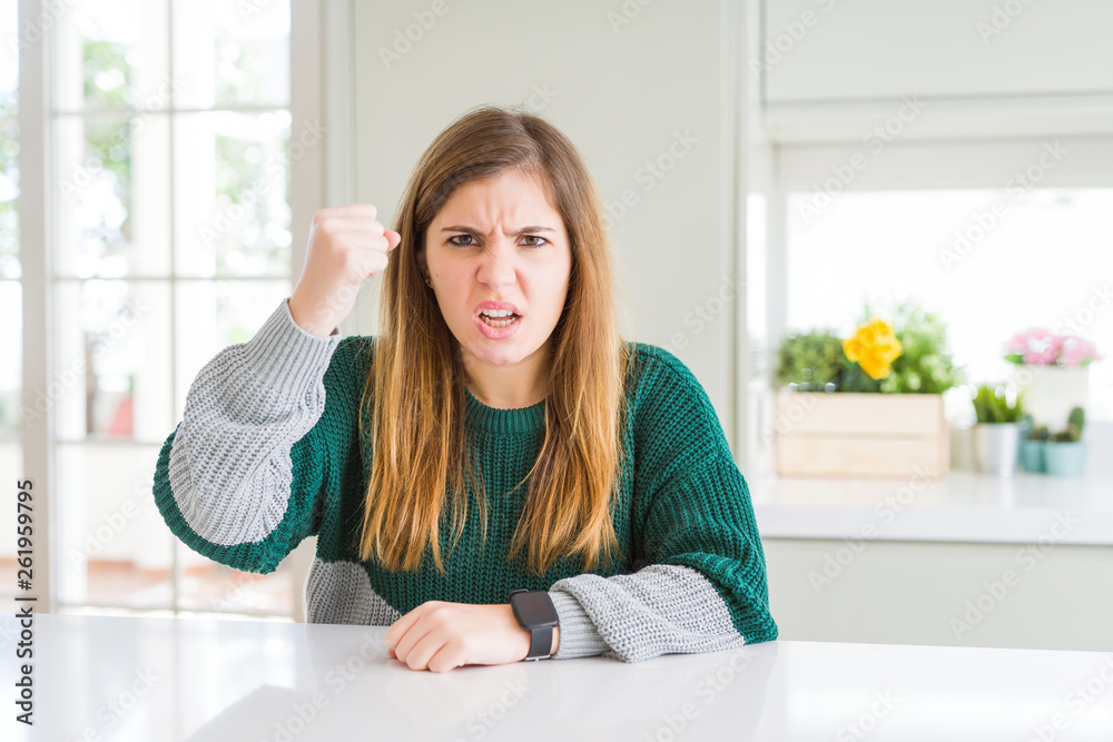 Young beautiful plus size woman wearing casual striped sweater angry and mad raising fist frustrated and furious while shouting with anger. Rage and aggressive concept. Young beautiful plus size woman wearing casual striped sweater angry and mad raising fist frustrated and furious while shouting with anger. Rage and aggressive concept.