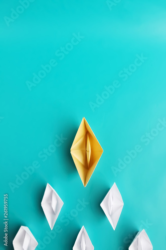 teambuilding and leadership concept. White paper ships on blue background