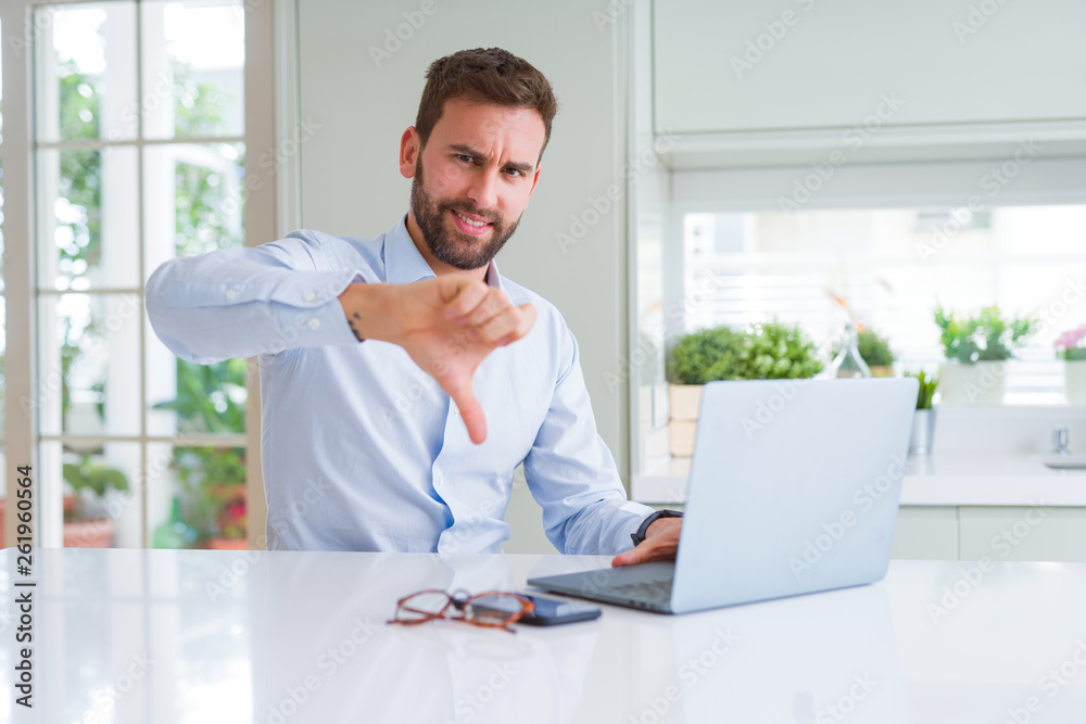 Handsome business man working using computer laptop with angry face, negative sign showing dislike with thumbs down, rejection concept