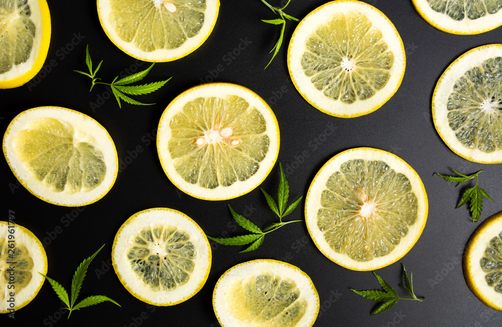 Sliced lemons and marijuana on a dark background