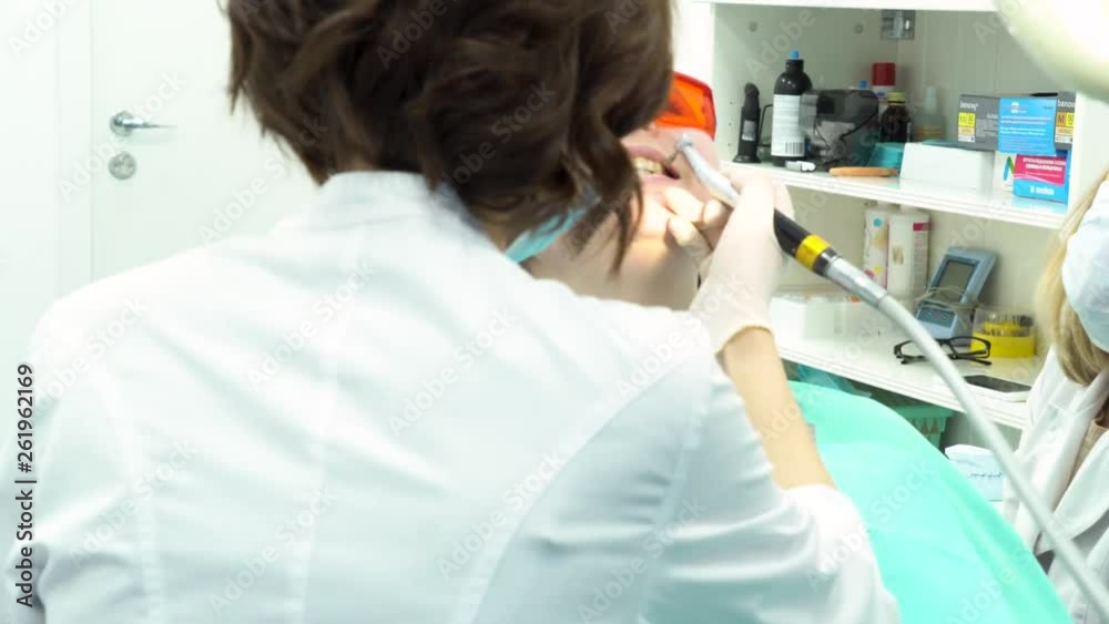 Professional dental cleaning of female patient teeth at dental clinic