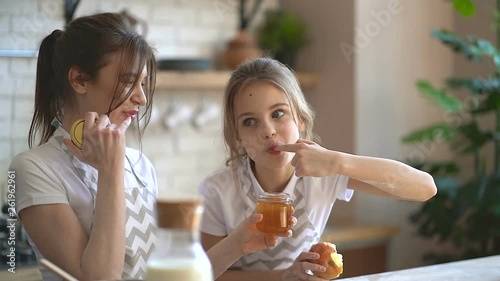 Two sisters at the kitchen. Testing food, eating honey.