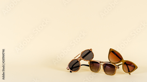 Wooden sunglasses of different design on yellow background. Copy space. Sunglasses sale concept. For banner optic shop