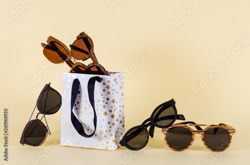 Sunglasses sale concept. Different sunglasses in shoping bags on yellow background. Fashion summer accessories. Copy space