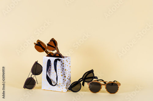 Wooden sunglasses of different design in shopping bag on yellow background. Sunglasses sale concept. Fashion summer accessories. Close up