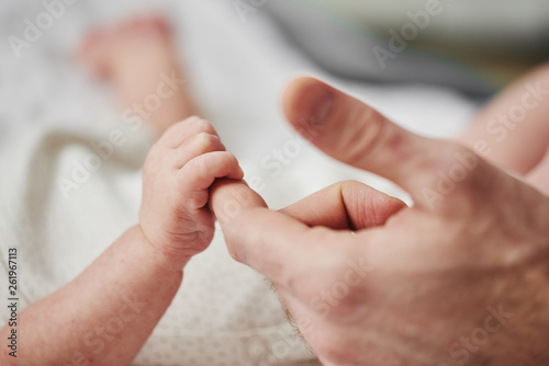 The little hand of the baby holds the finger of its parents.