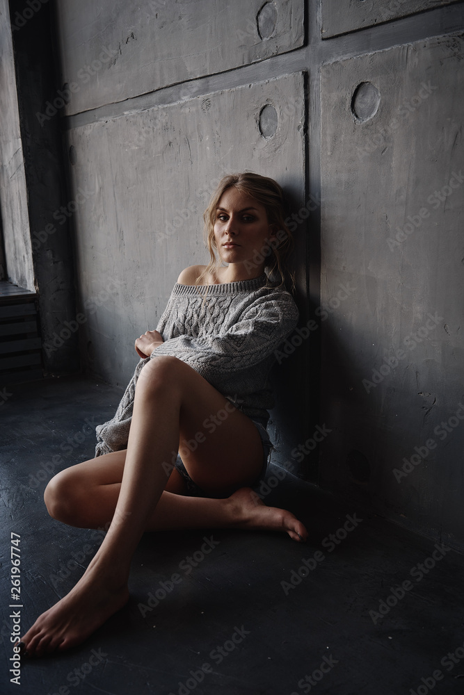 Beautiful girl sitting on the background of a concrete wall