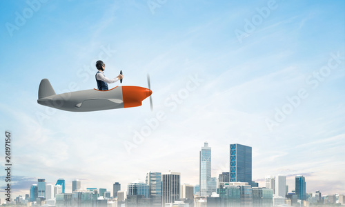 Businessman driving propeller plane above downtown