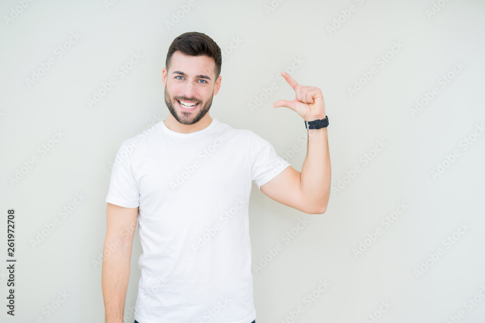 Young handsome man wearing casual white t-shirt over isolated background smiling and confident gesturing with hand doing size sign with fingers while looking and the camera. Measure concept. Young handsome man wearing casual white t-shirt over isolated background smiling and confident gesturing with hand doing size sign with fingers while looking and the camera. Measure concept.