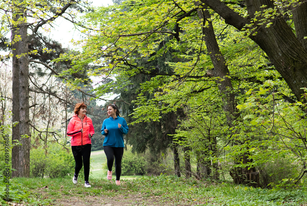 Mother and daughter wearing sportswear and running in forest Mother and daughter wearing sportswear and running in forest