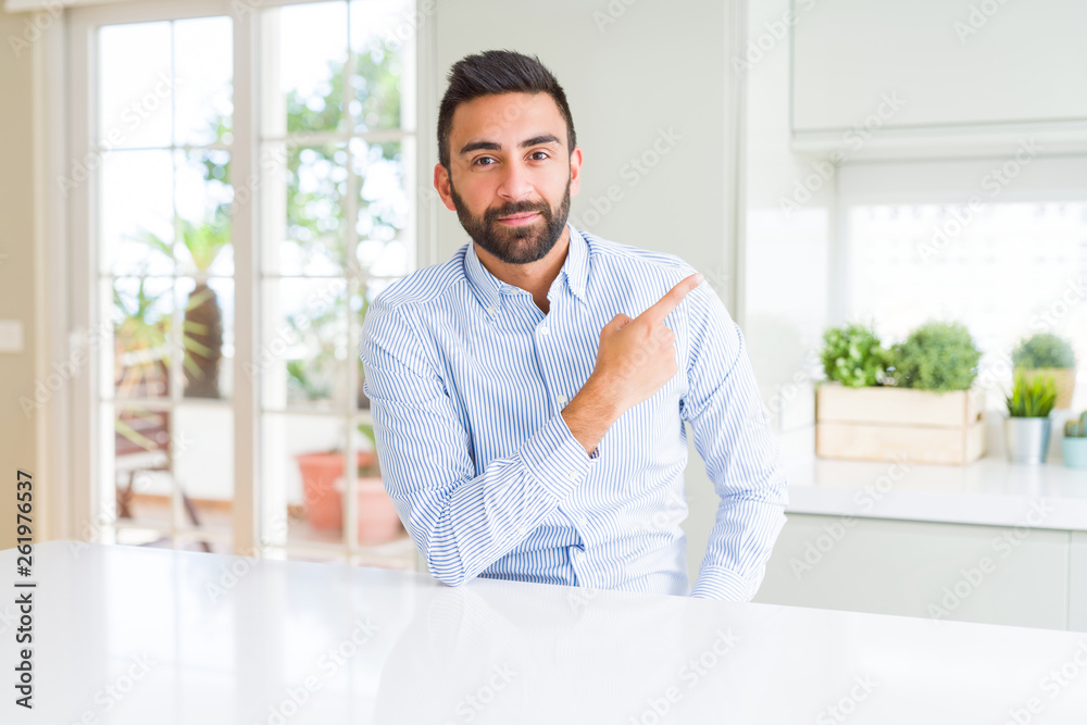 Handsome hispanic business man Pointing with hand finger to the side showing advertisement, serious and calm face