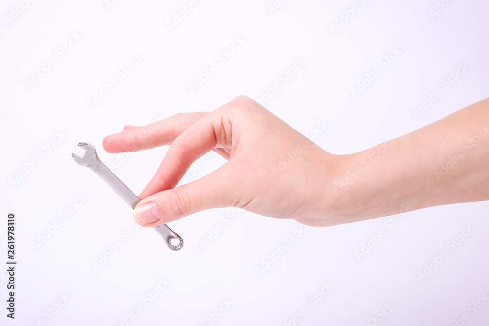 A wrench in the hand of a girl. Symbol of hard work, feminism and labor day. Isolate on white background. A wrench in the hand of a girl. Symbol of hard work, feminism and labor day. Isolate on white background.