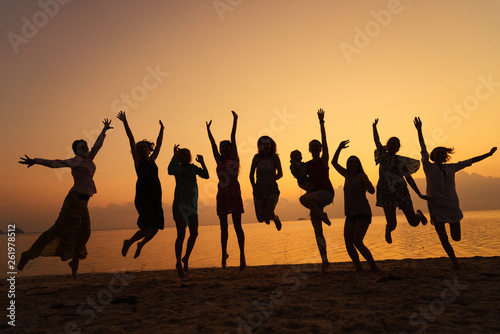 Silhouettes of women jumping on the sea beach at sunset