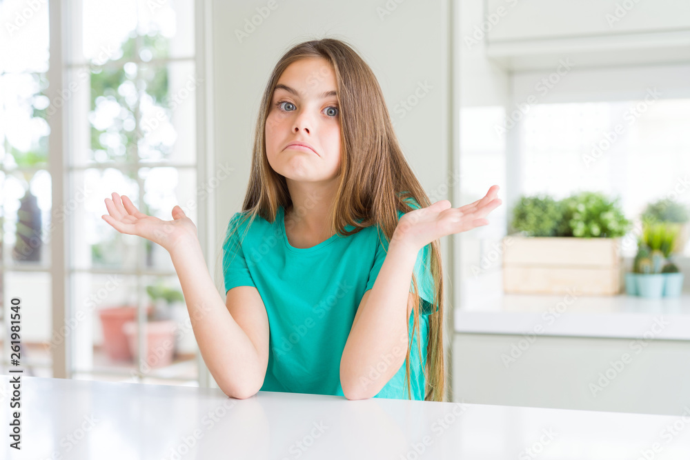Beautiful young girl kid wearing green t-shirt clueless and confused expression with arms and hands raised. Doubt concept. Beautiful young girl kid wearing green t-shirt clueless and confused expression with arms and hands raised. Doubt concept.