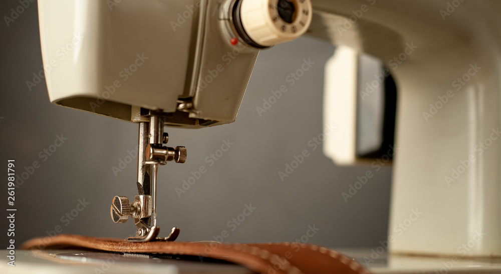 Background type of sewing machine, leather belt sewing process. Leather workshop.