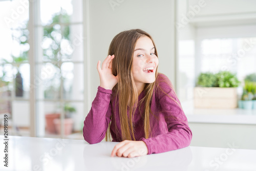 Beautiful young girl kid on white table smiling with hand over ear listening an hearing to rumor or gossip. Deafness concept. Free Download Beautiful young girl kid on white table smiling with hand over ear listening an hearing to rumor or gossip. Deafness concept. - GFXLoad