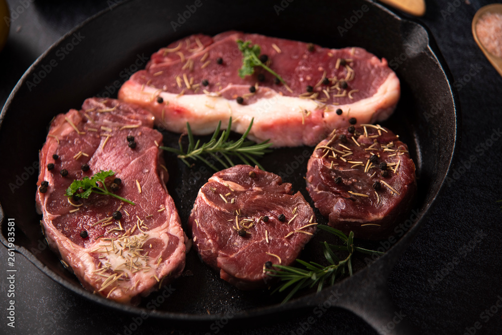 Raw beef fillet steaks with spices on wooden background