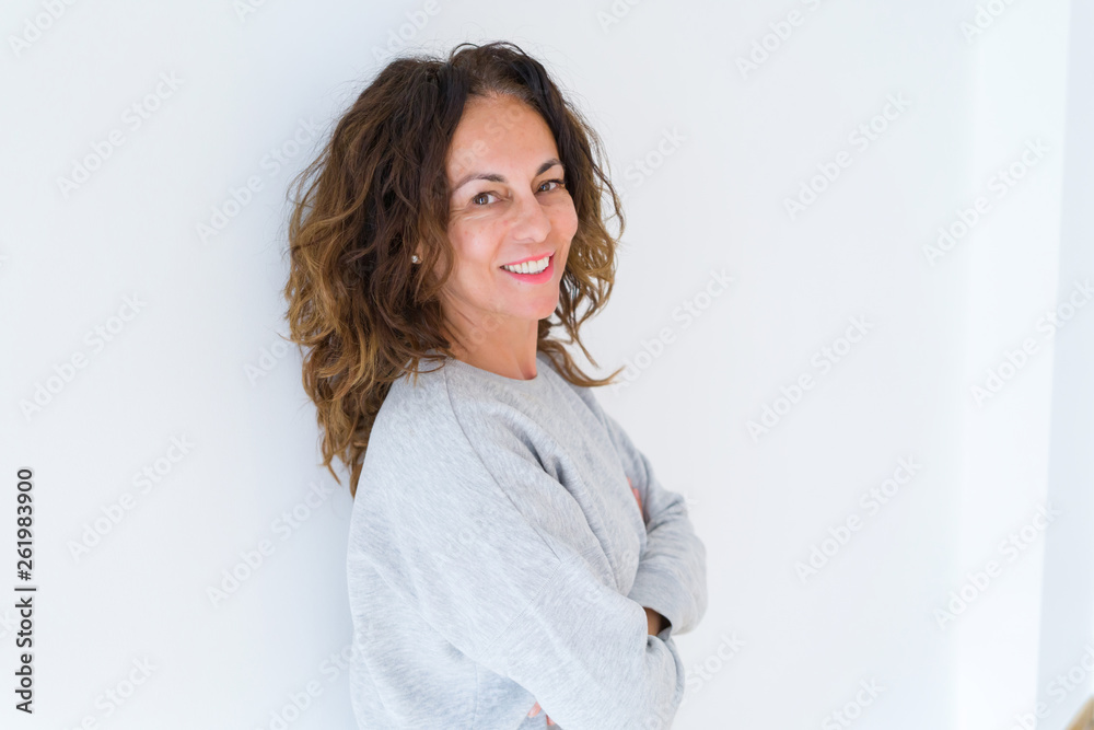 Beautiful middle age woman with curly hair smiling cheerful and happy with arms crossed, laughing with a big smile on face showing teeth over white isolated background Beautiful middle age woman with curly hair smiling cheerful and happy with arms crossed, laughing with a big smile on face showing teeth over white isolated background
