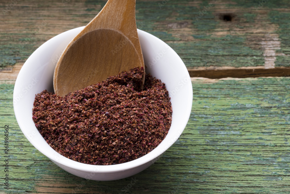 Ground sumac spice in white bowl, traditional Arabic ingredient for