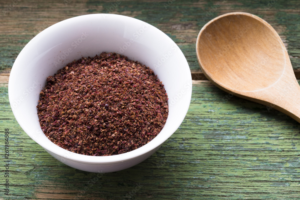 Ground sumac spice in white bowl, traditional Arabic ingredient for