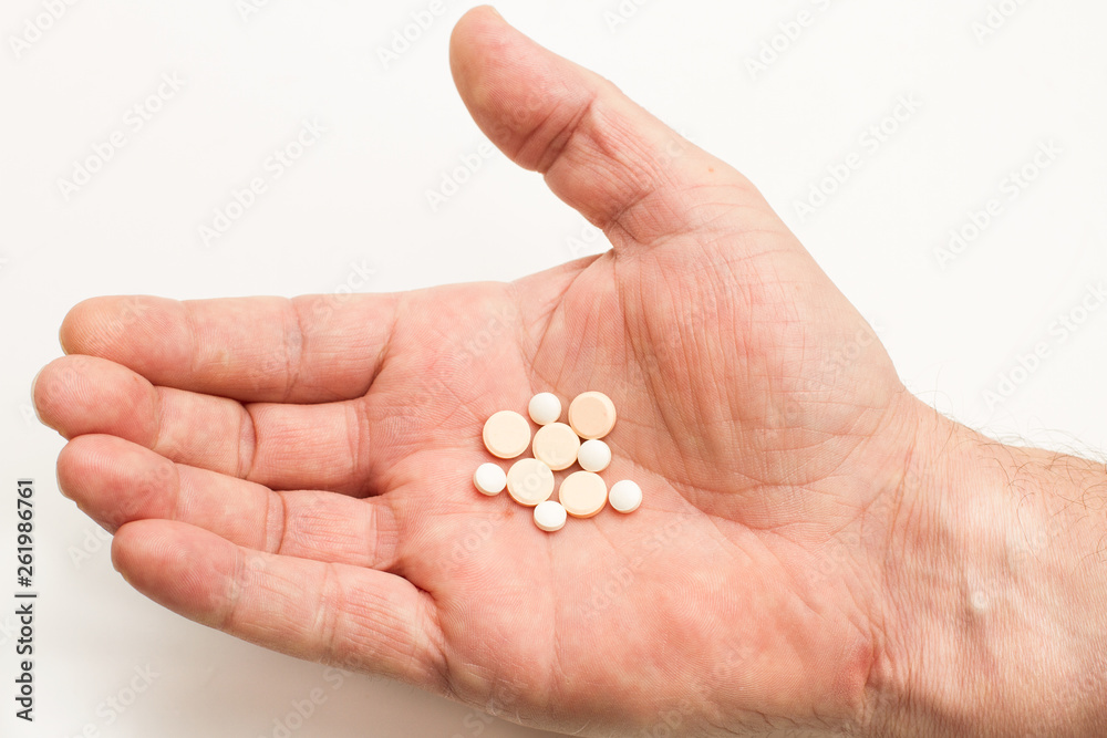 Mano de hombre abierta sosteniendo medicamentos en primer plano. Fondo blanco. Concepto: Salud Medicina Mano de hombre abierta sosteniendo medicamentos en primer plano. Fondo blanco. Concepto: Salud Medicina