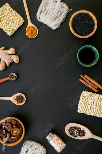 Chinese and Japanese food cooking with ginger, spices and noodles frame on black background top view space for text