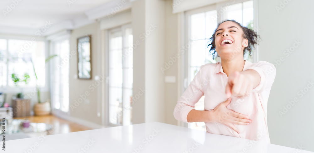 Wide angle of beautiful african american woman with afro hair laughing at you, pointing finger to the camera with hand over body, shame expression Wide angle of beautiful african american woman with afro hair laughing at you, pointing finger to the camera with hand over body, shame expression