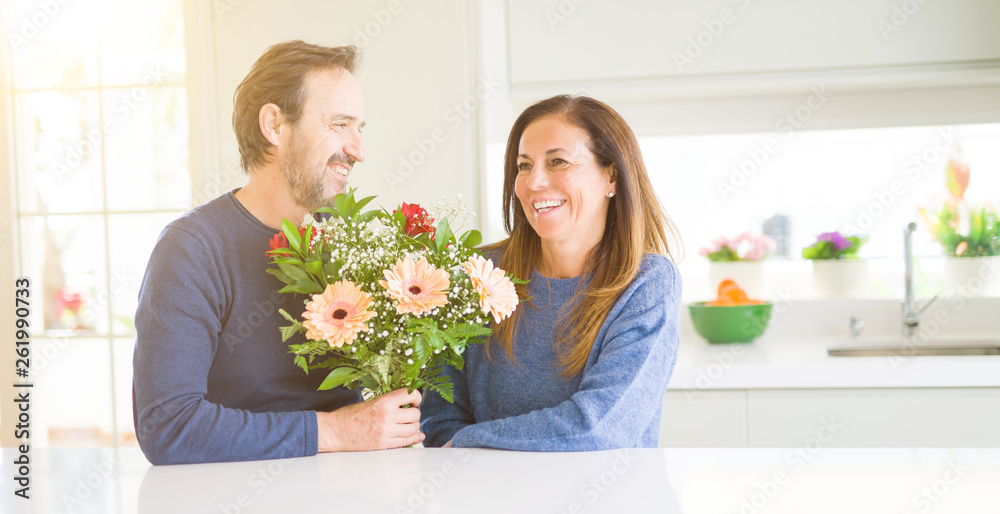 Romantic middle age couple holding flowers in love at home Romantic middle age couple holding flowers in love at home