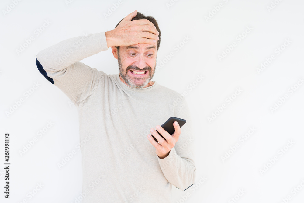 Senior man using smartphone over isolated background stressed with hand on head, shocked with shame and surprise face, angry and frustrated. Fear and upset for mistake. Senior man using smartphone over isolated background stressed with hand on head, shocked with shame and surprise face, angry and frustrated. Fear and upset for mistake.