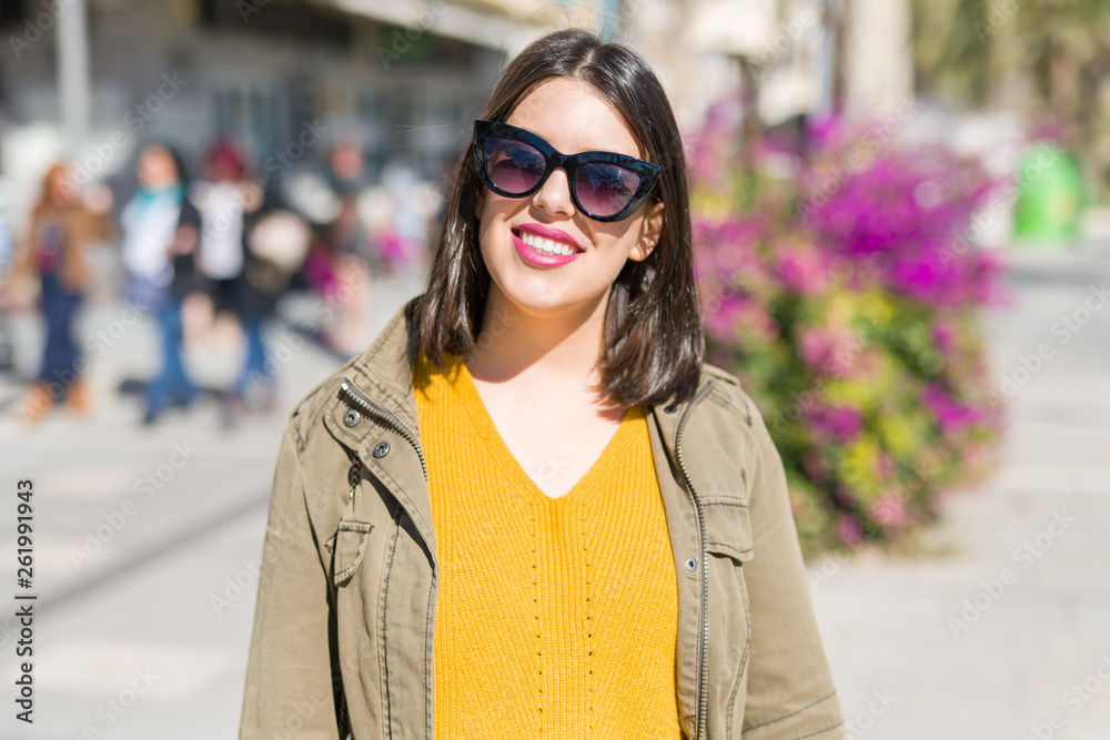 Beautiful young woman smiling cheerful walking on the street on a sunny day wearing sunglasses, casual pretty girl at the town Beautiful young woman smiling cheerful walking on the street on a sunny day wearing sunglasses, casual pretty girl at the town