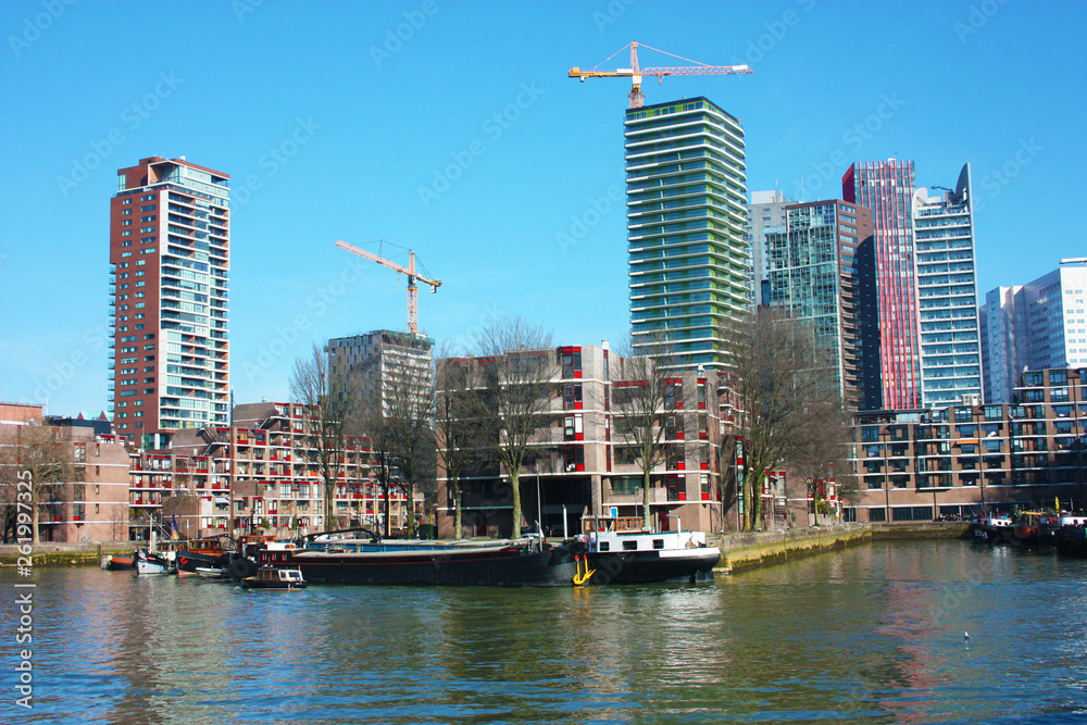 Obraz premium The modern and touristic port of Rotterdam on a sunny spring day. In the metropolis boats, ships and fishing boats wake up in the morning ready for work.