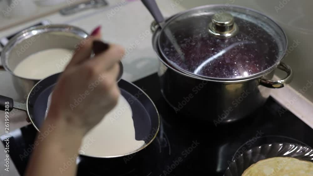 The process of cooking homemade pancakes. Woman pours pancake dough on pan The process of cooking homemade pancakes. Woman pours pancake dough on pan